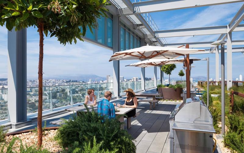 a group of people sitting at a table on a deck overlooking a city